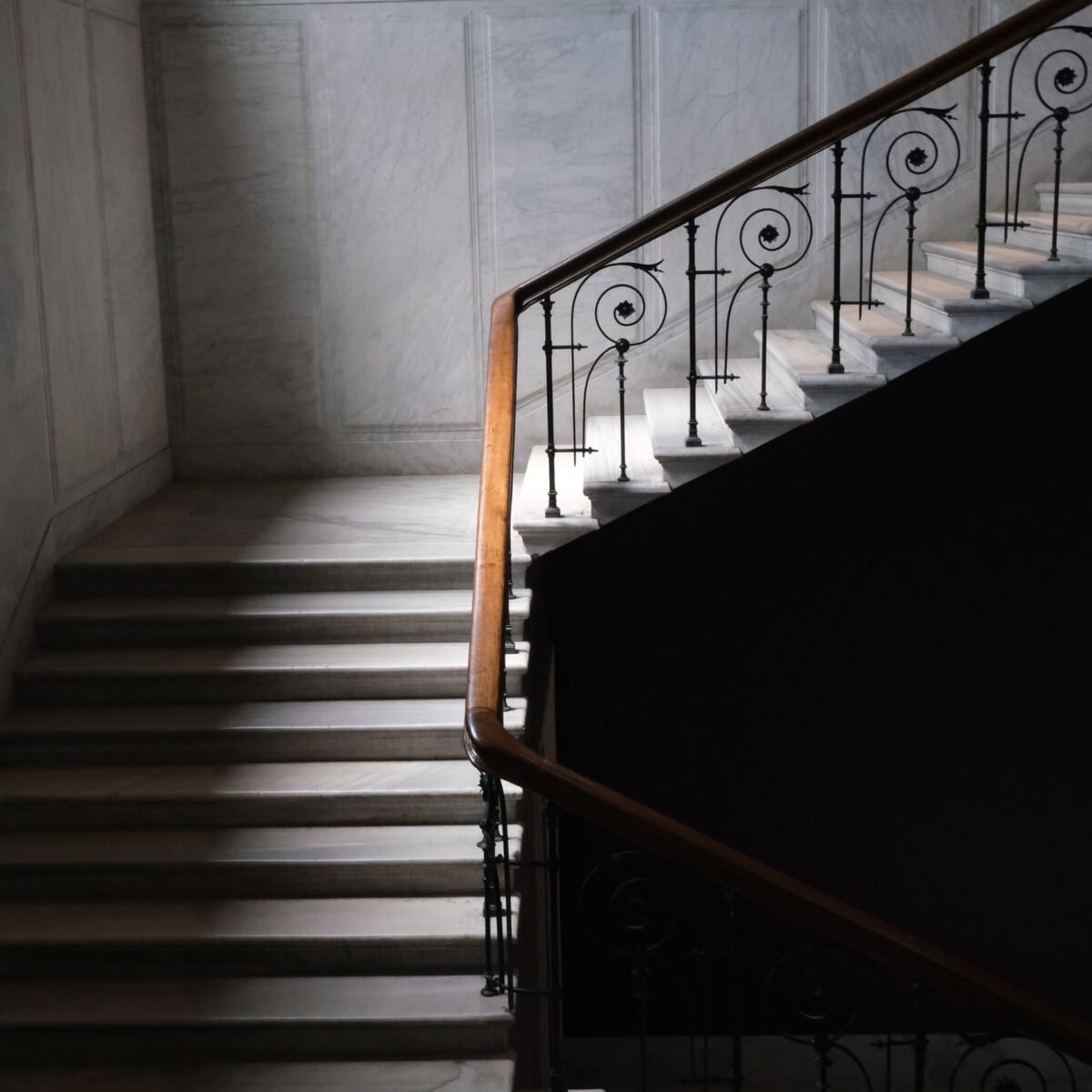 Escalier en marbre à balustrade en fer forgé, éclairé par la lumière naturelle