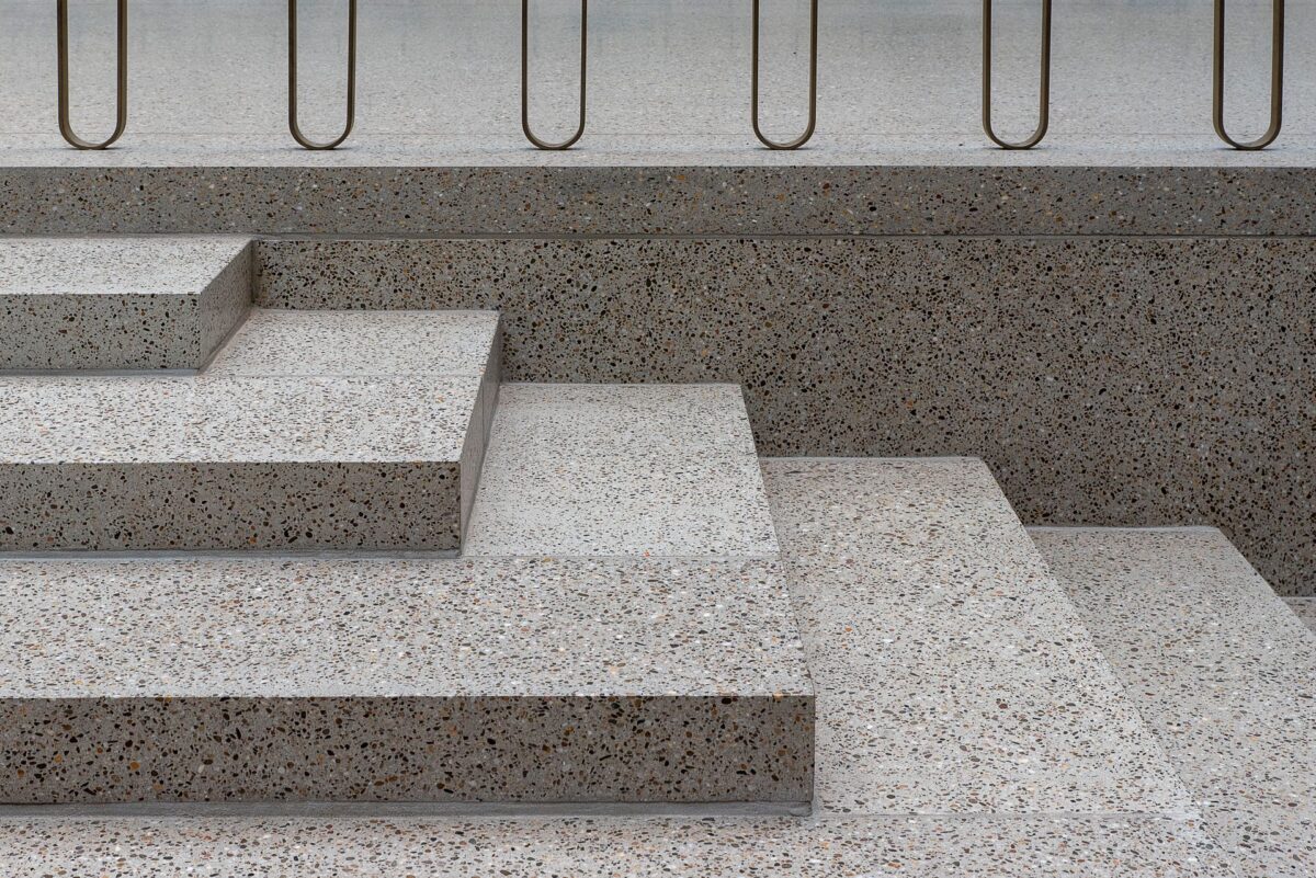 Escalier minimaliste aux marches en terrazzo gris et rampe métallique