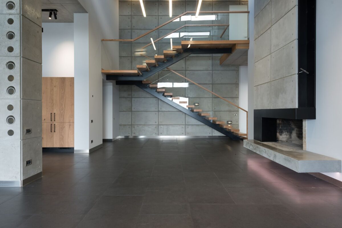 Intérieur avec escalier flottant et cheminée sur un sol gris grand format
