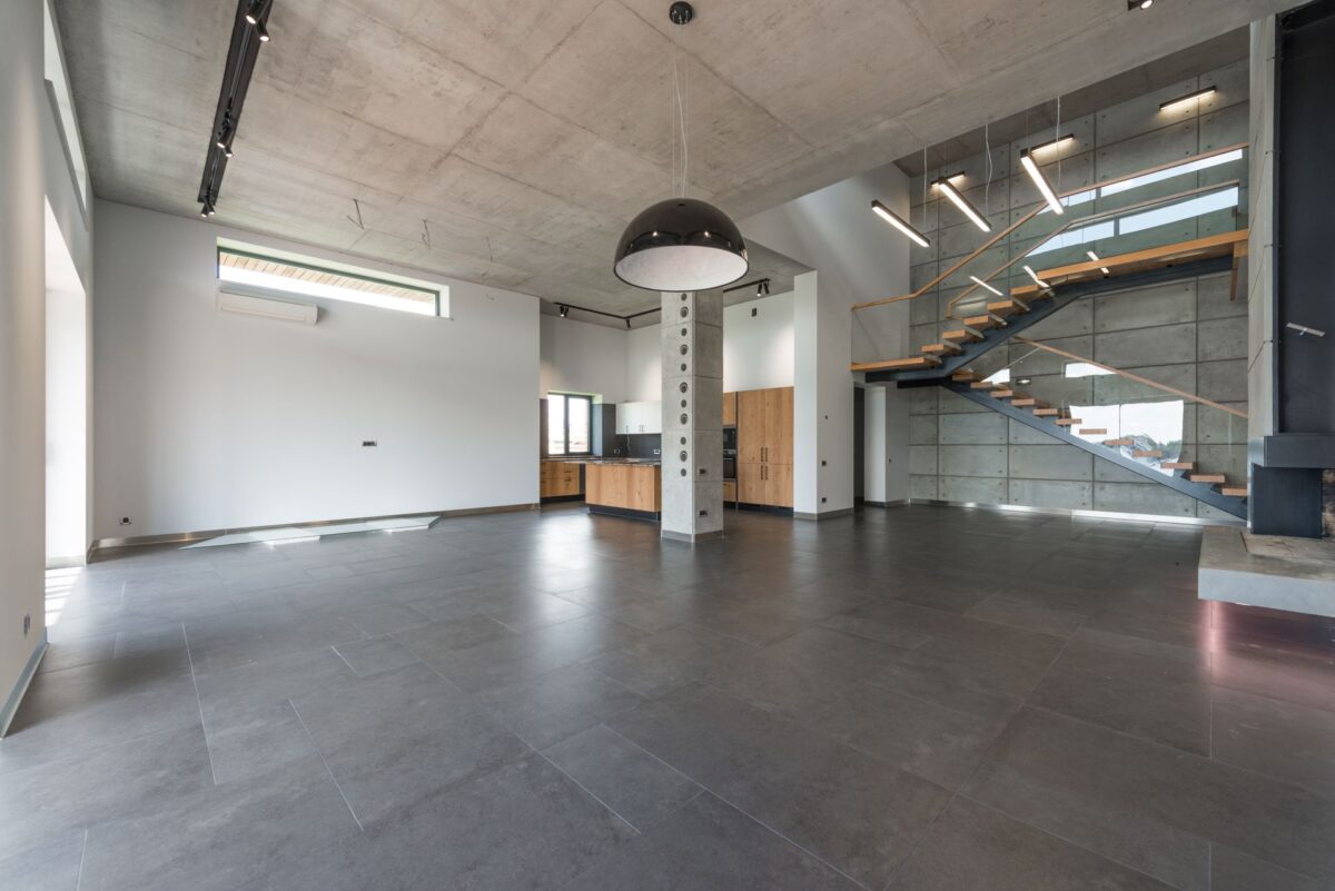 Loft avec escalier ouvert et sol en carrelage gris grand format sous une lumière naturelle abondante