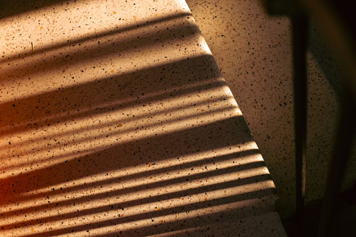 Lumière rasante sur les éclats d'un escalier en terrazzo massif