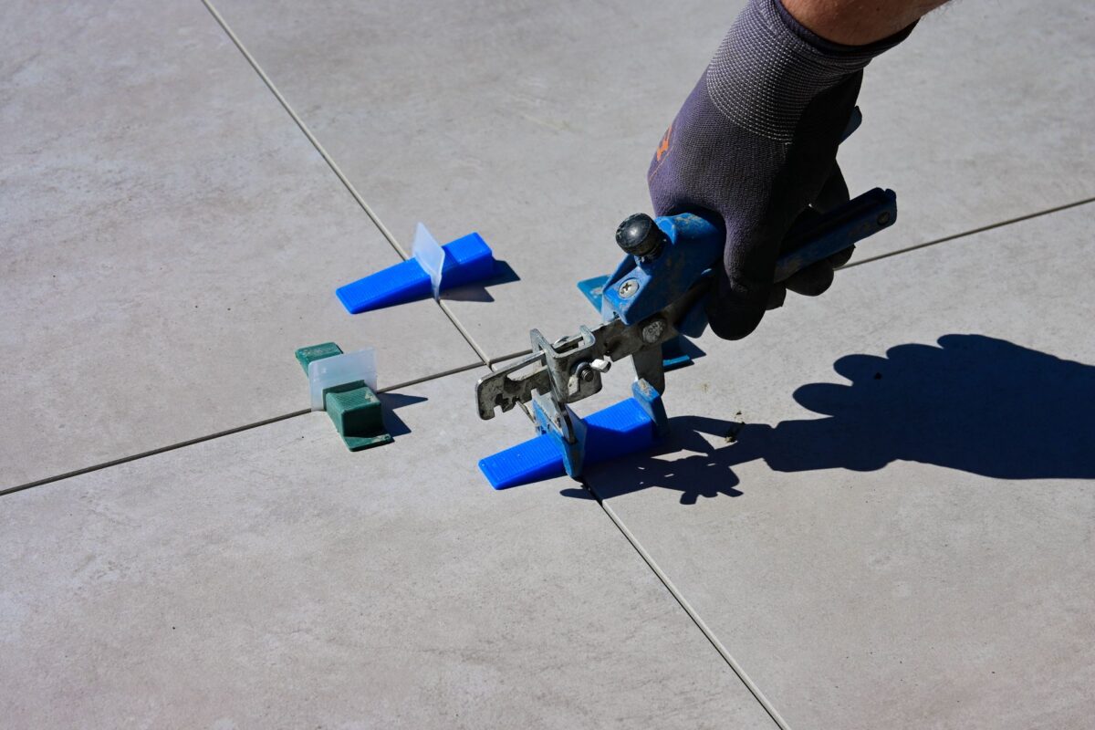 Main posant des croisillons d'espacement sur un carrelage clair