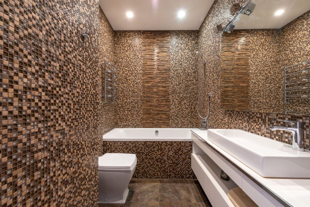 Salle de bain habillée de mosaïque beige avec baignoire et plan vasque