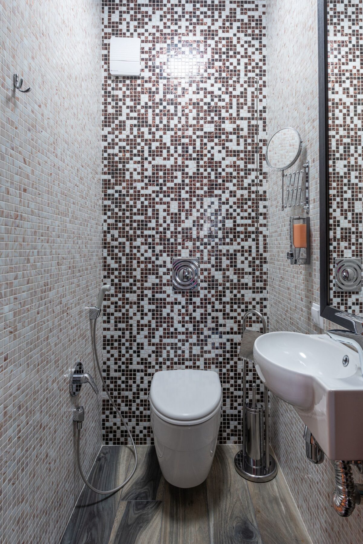 Mur de douche en mosaïque brune et blanche avec WC et lavabo