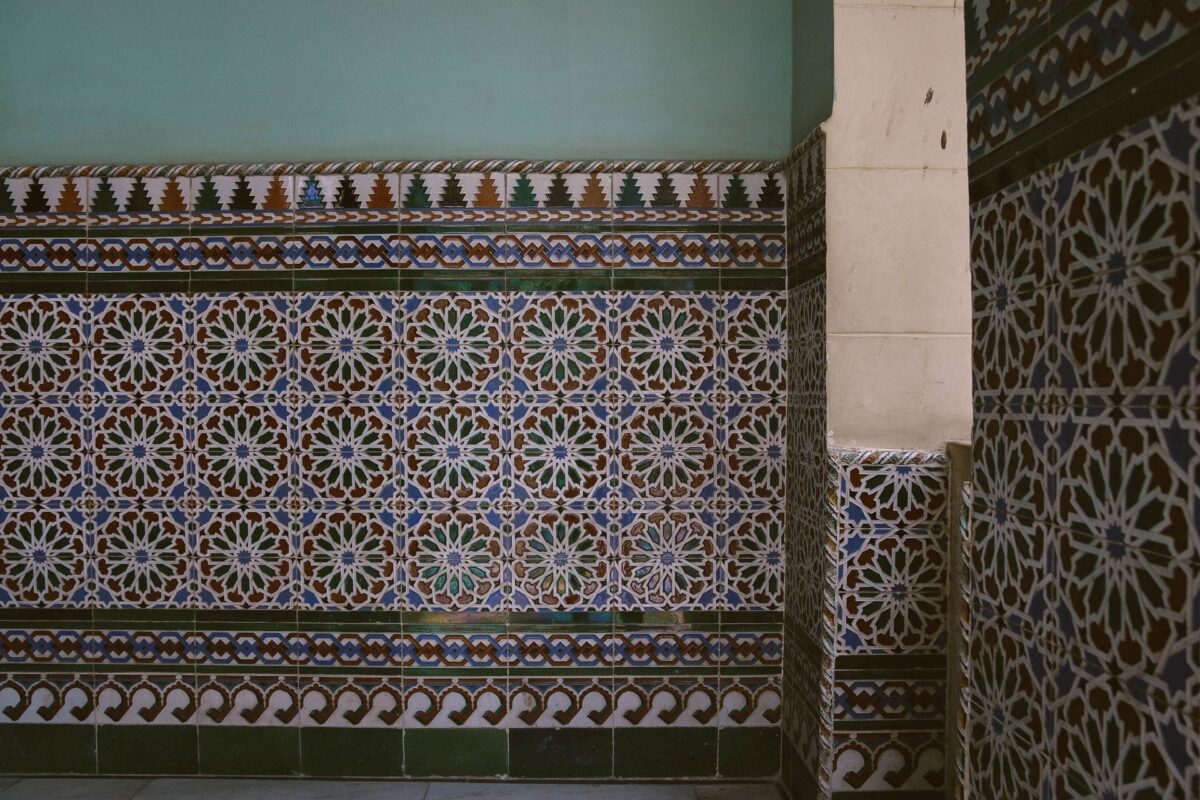 Mur en mosaïque marocaine à motifs géométriques bleus, blancs et orangés, joints très fins