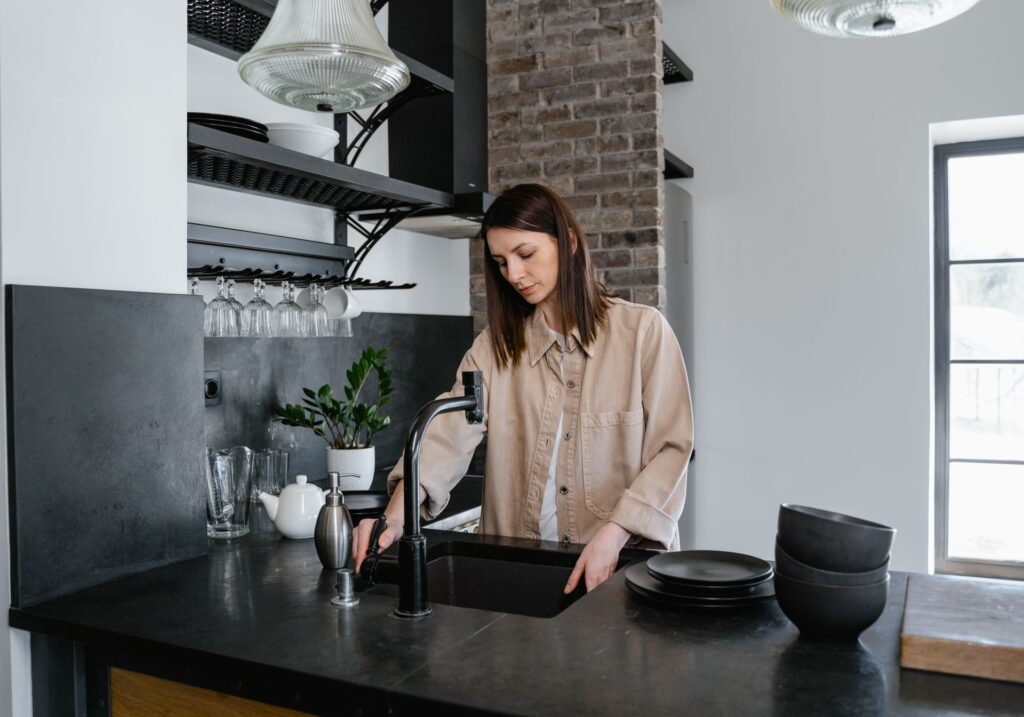 Personne faisant la vaisselle dans une cuisine au plan de travail sombre