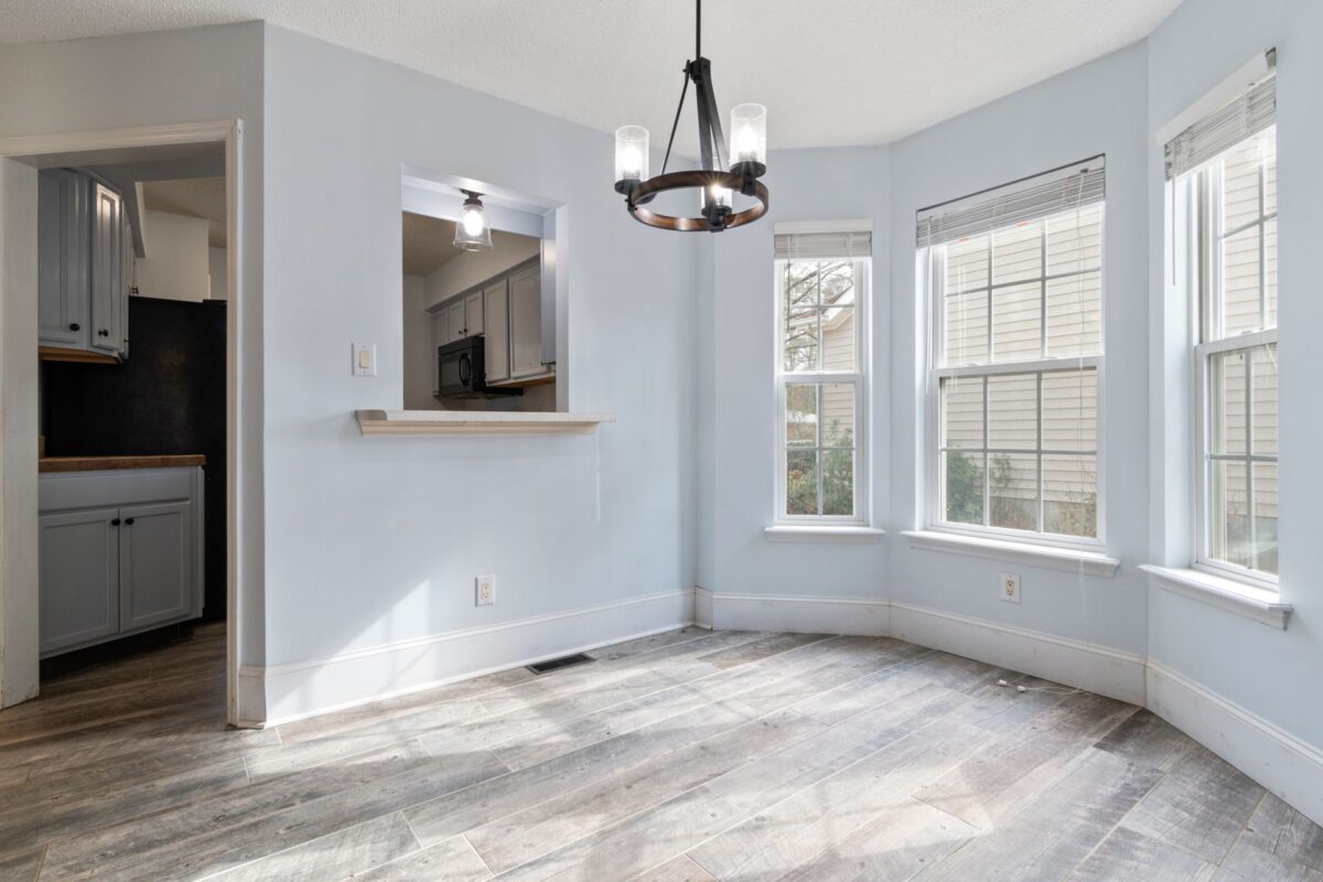Pièce vide et lumineuse avec sol en carrelage imitation parquet clair et lustre suspendu