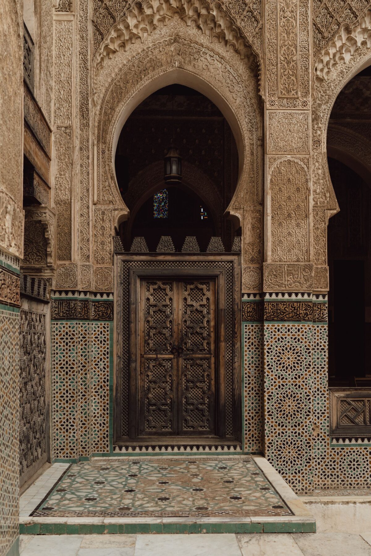 Porte marocaine en bois sculpté encadrée de mosaïque, symbole de l'artisanat de Fès