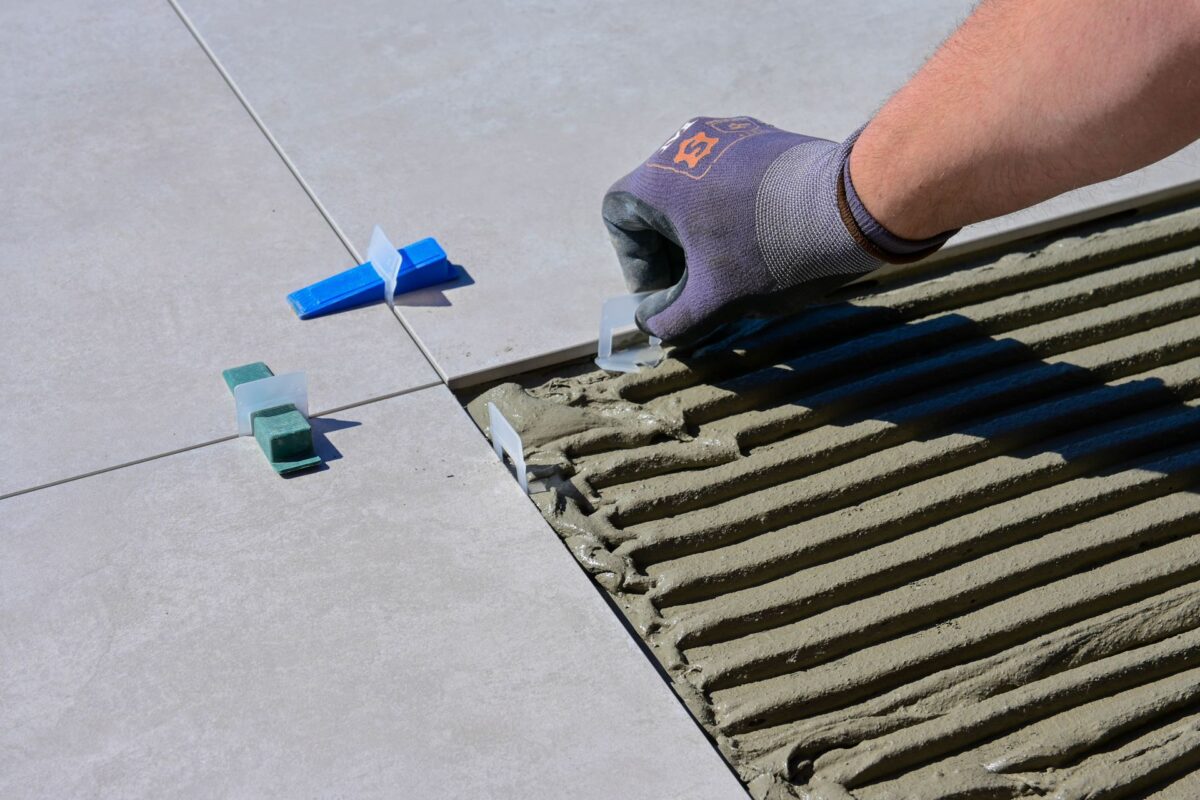Pose de carrelage avec cales de nivellement sur mortier frais