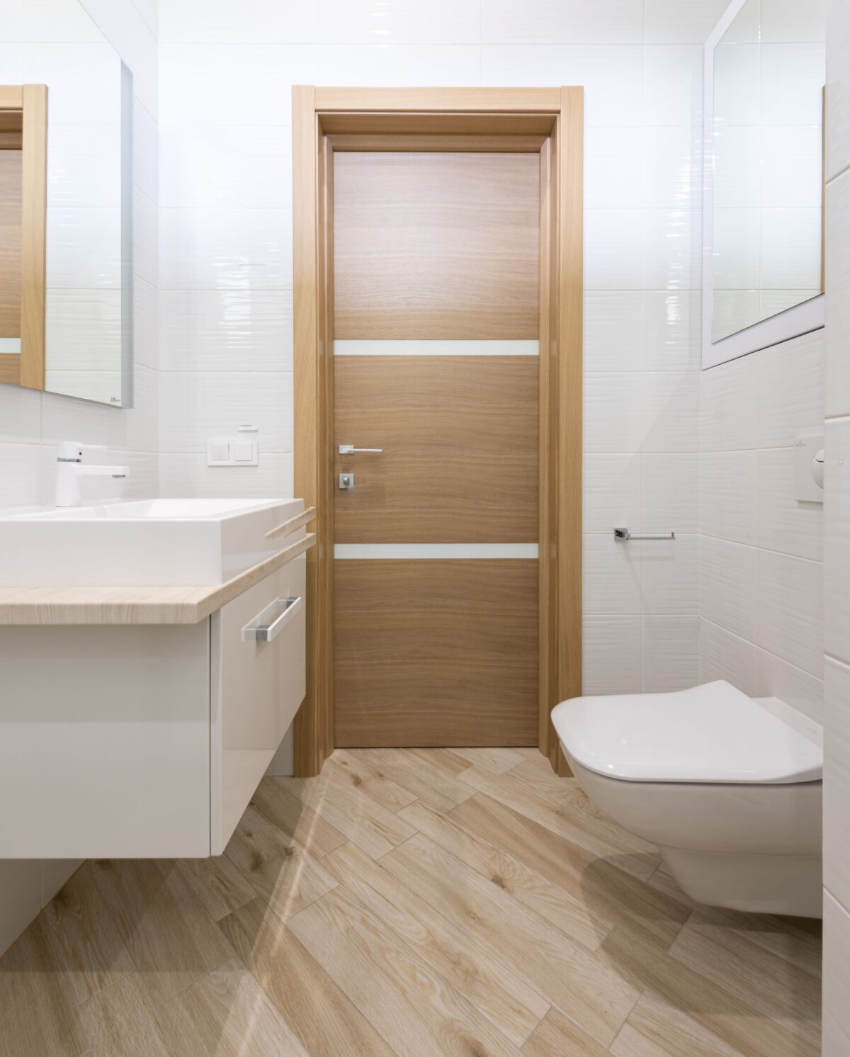 Salle de bain avec sol clair en carrelage imitation parquet et porte en bois assortie