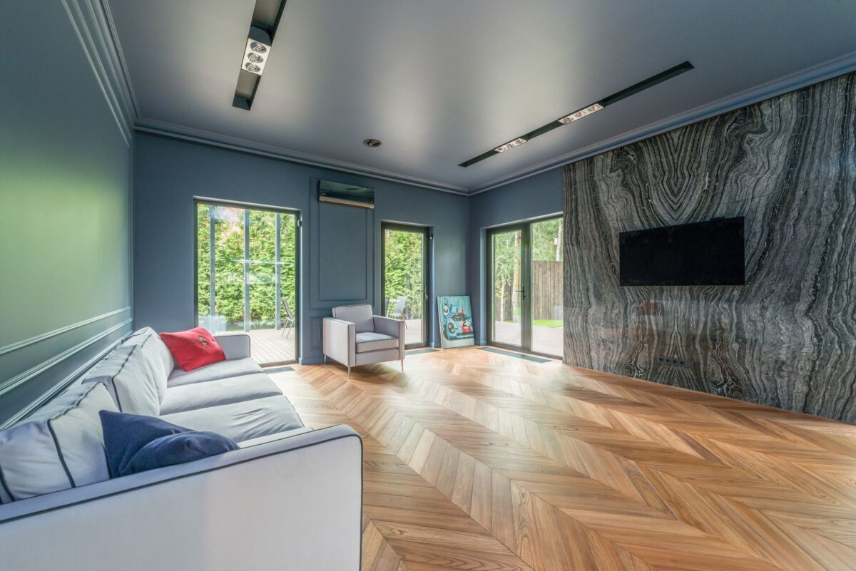 Salon avec sol en carrelage imitation parquet posé en chevrons et mur en marbre