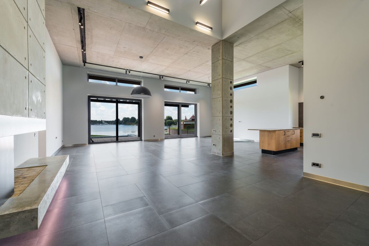 Salon lumineux avec un sol en dalles de carrelage gris clair grand format et une grande baie vitrée