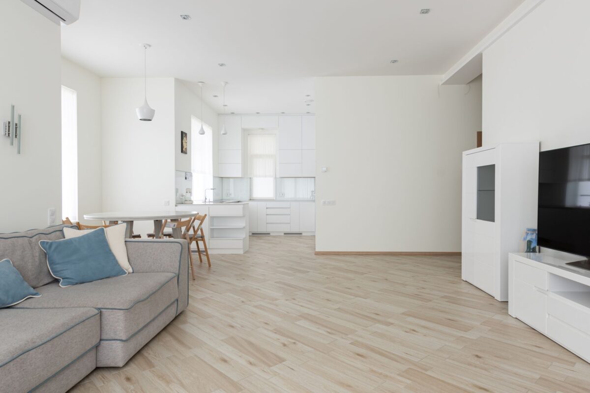 Salon lumineux ouvert sur une cuisine avec sol clair en carrelage imitation parquet