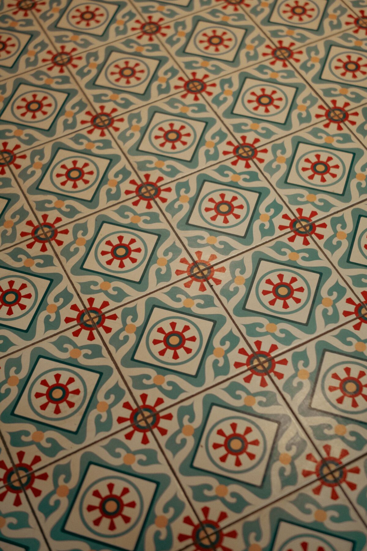 Sol en carreaux de ciment à médaillons floraux rouges et verts sur fond blanc