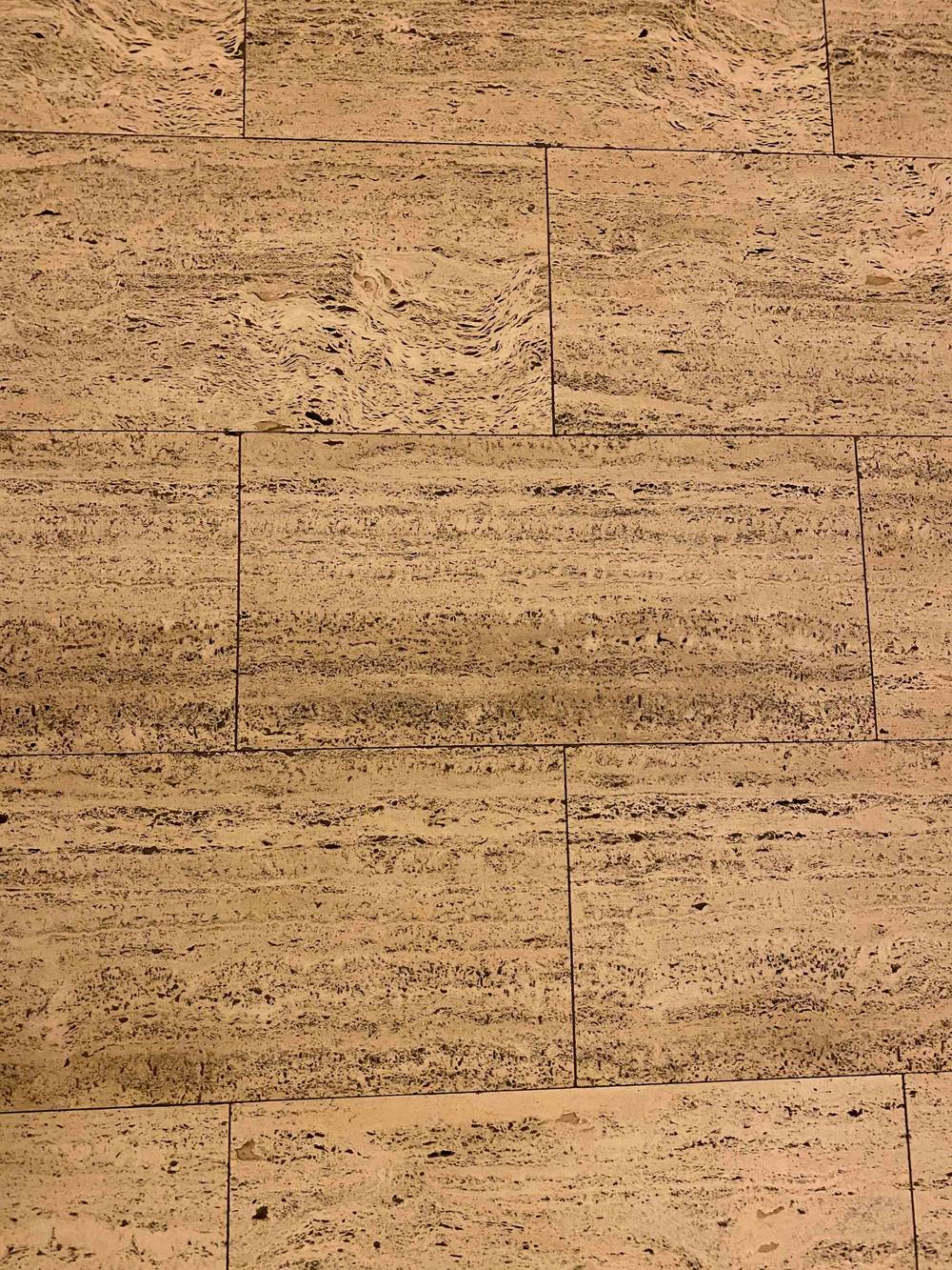 Sol en carrelage effet travertin beige avec un veinage linéaire