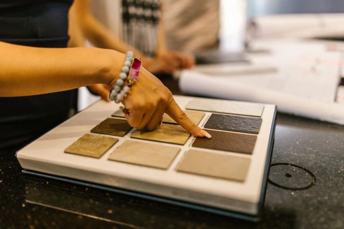 Une main désigne un échantillon parmi une palette de carreaux présentée en showroom