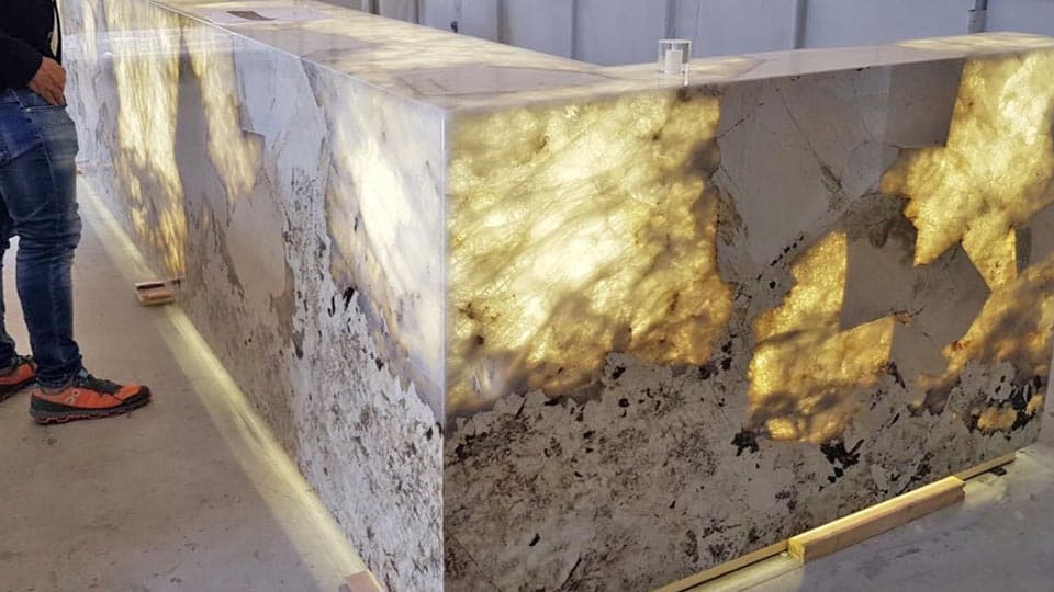 Habillage de bar rétroéclairé en granit Patagonia, les inclusions de cristal de roche laissent passer la lumière