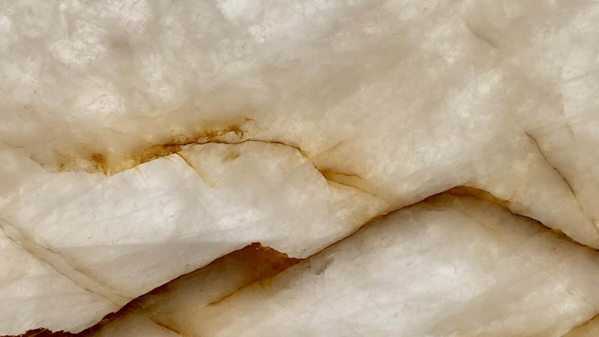 Tranche de cristal de roche polie, quartz blanc translucide traversé de veines dorées