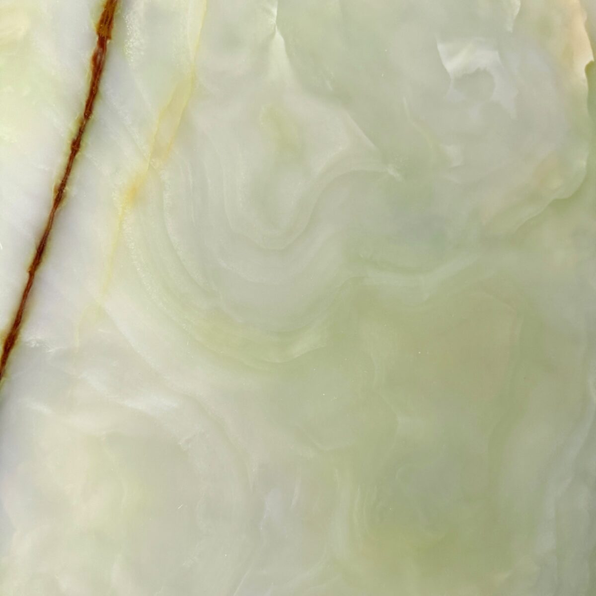 Tranche d’onyx vert pâle aux bandes concentriques, une veine brune sur le bord