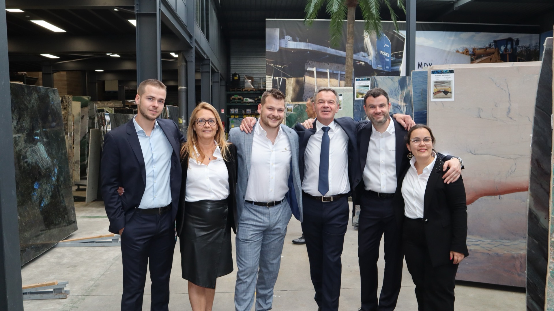 Photo de famille MDY, six personnes devant les tranches de pierre de l'entrepôt