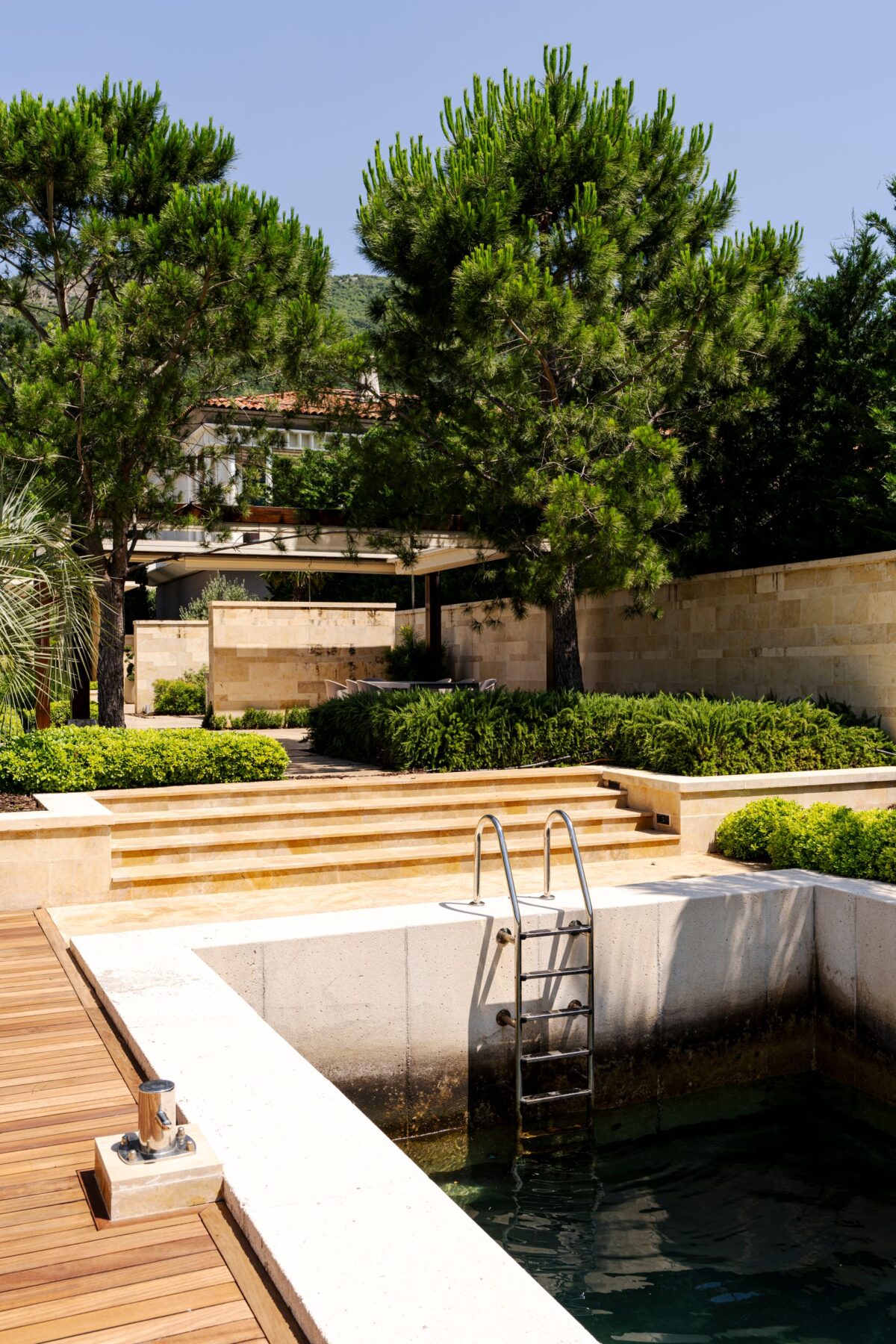 Piscine contemporaine à margelles en pierre grise et terrasse en bois
