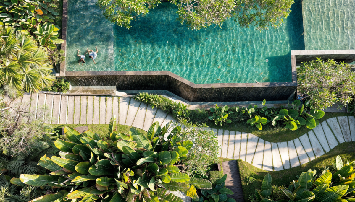 Piscine vue du dessus avec plage et escaliers en pierre dans un jardin tropical