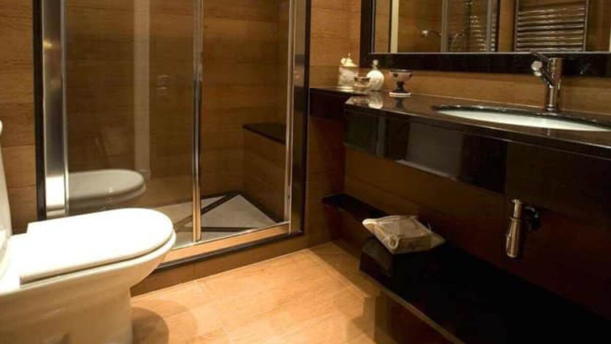 Salle de bains au sol en carrelage aspect bois clair avec meuble et plan sombres